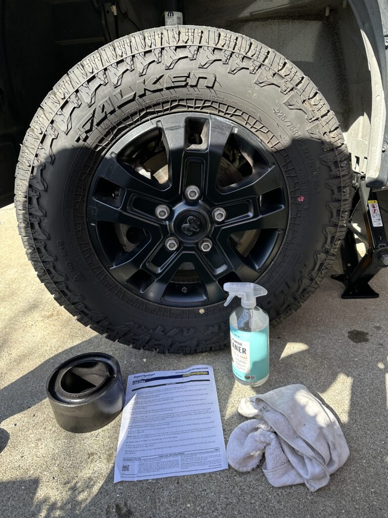 a sumo spring, instruction sheet, cleaner spray bottle and a rag sitting in front of a van wheel